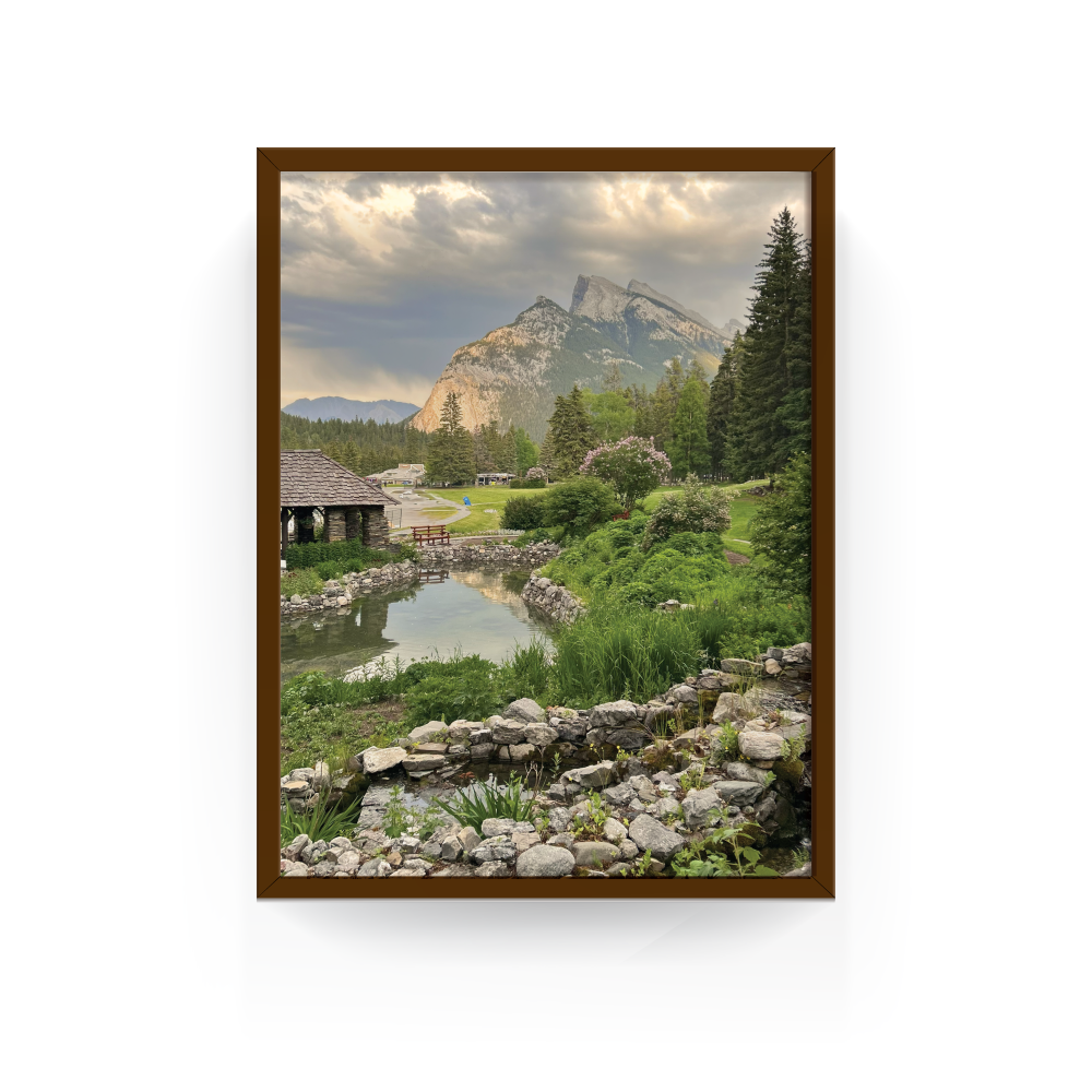 Vertical Banff cityscape print with espresso frame capturing peaceful garden and rugged mountain views