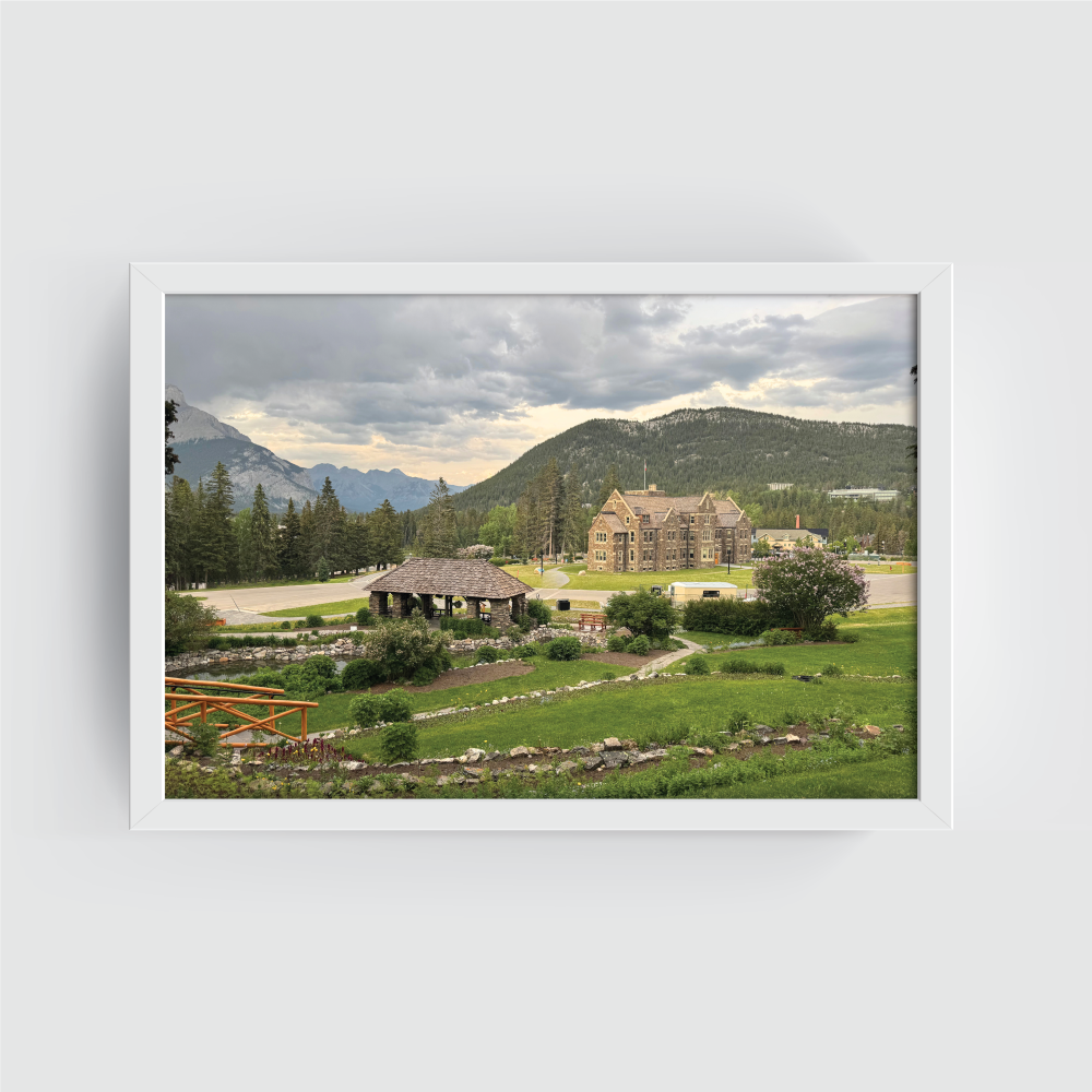 Horizontal Banff cityscape print with white frame emphasizing lush garden, pavilion, and mountain horizon