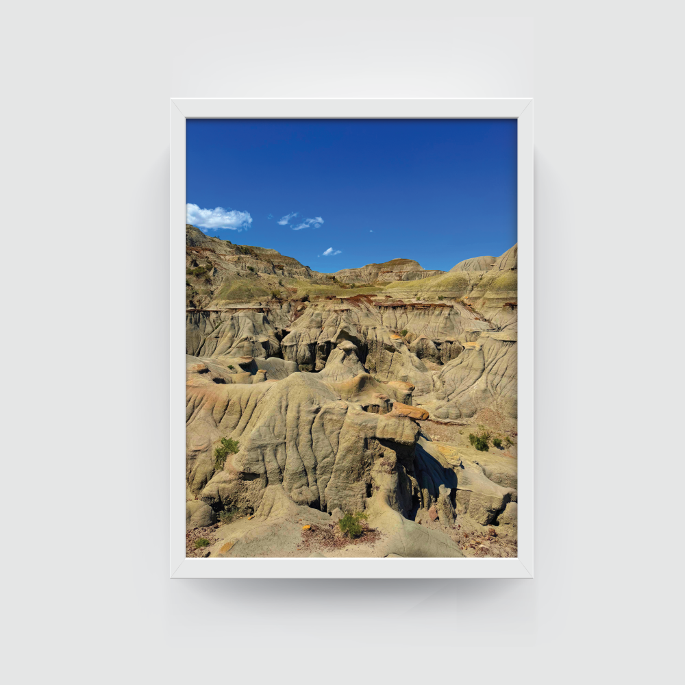 Vertical white-framed Canadian Badlands landscape featuring eroded cliffs and layered hills at Dinosaur Provincial Park.