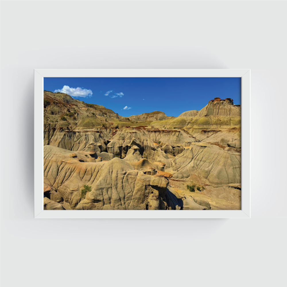 Horizontal white-framed Canadian Badlands panorama showing eroded ridges and layered rock formations.