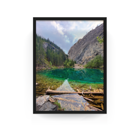 Black-framed photo of turquoise Grassi Lake in Canmore with surrounding forest and mountains.