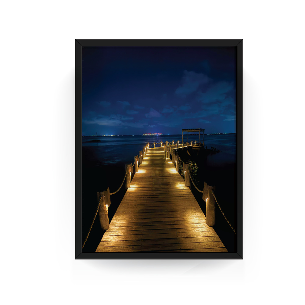 Black-framed night photograph of illuminated wooden pier over the Caribbean Sea at Nizuc Resort.