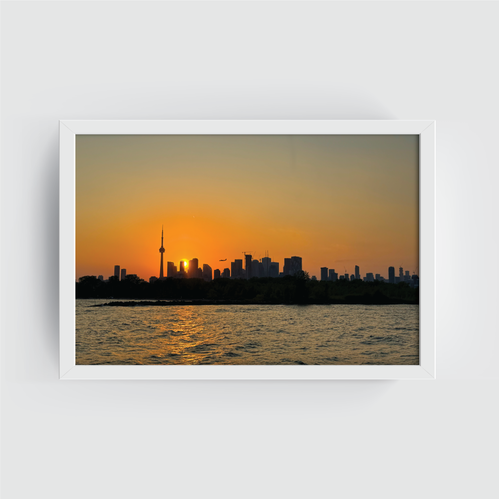 Toronto skyline at sunset photograph in a crisp white frame, highlighting warm orange and purple skies over downtown Toronto and the CN Tower waterfront view.